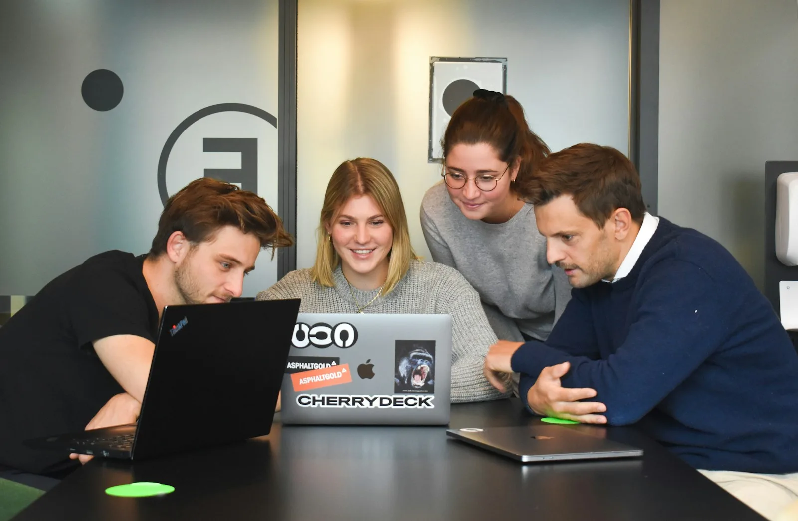Team collaborating around a laptop to track project progress