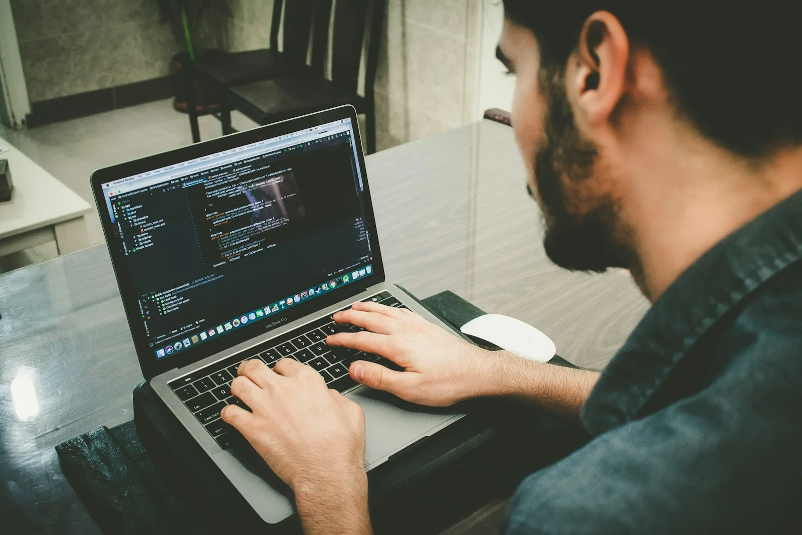 Developer writing code on a laptop with help from an AI agent