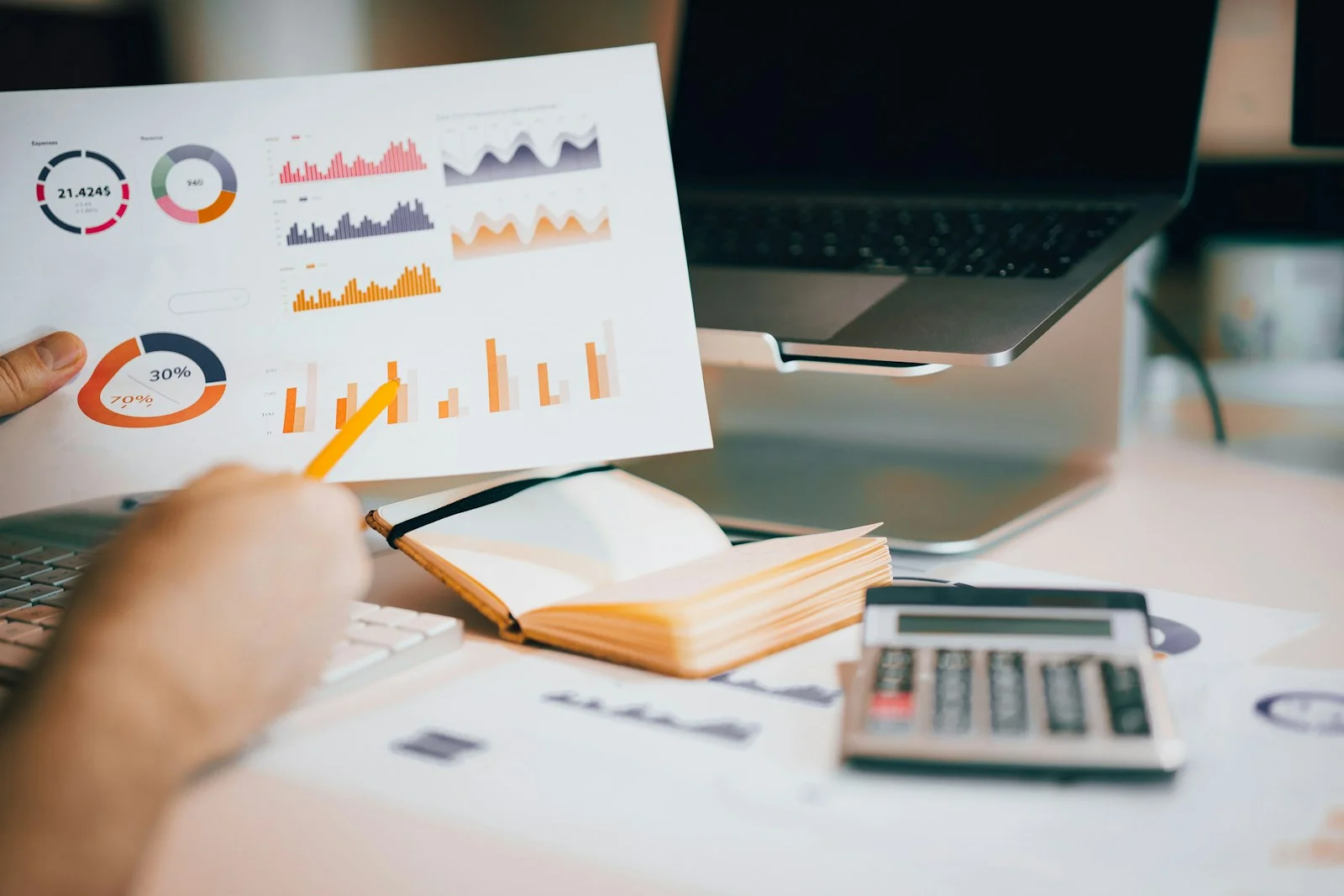Person reviewing a printed research report with charts beside a laptop